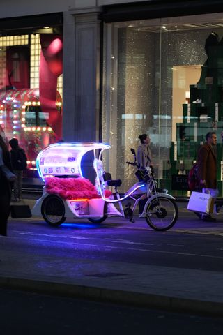 A neon lit rickshaw taxi parked up on shopping street in London