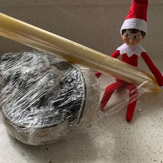 Elf on the shelf wrapping shoes in clingfilm