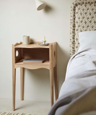 Dainty and decorative wooden bedside table with bed and upholstered headboard