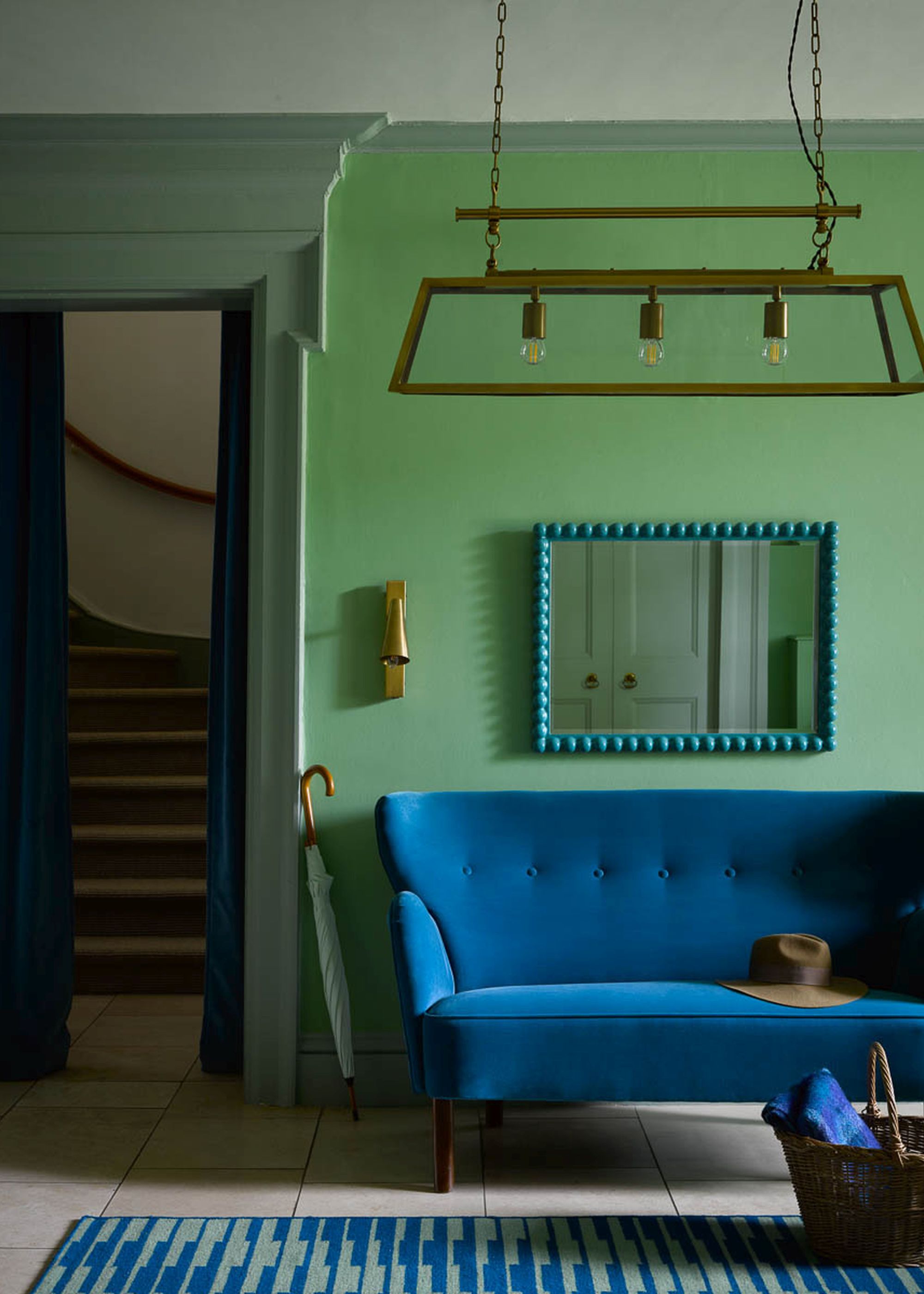living room with green walls, dark blue sofa, blue wall mirror with bobbled edge