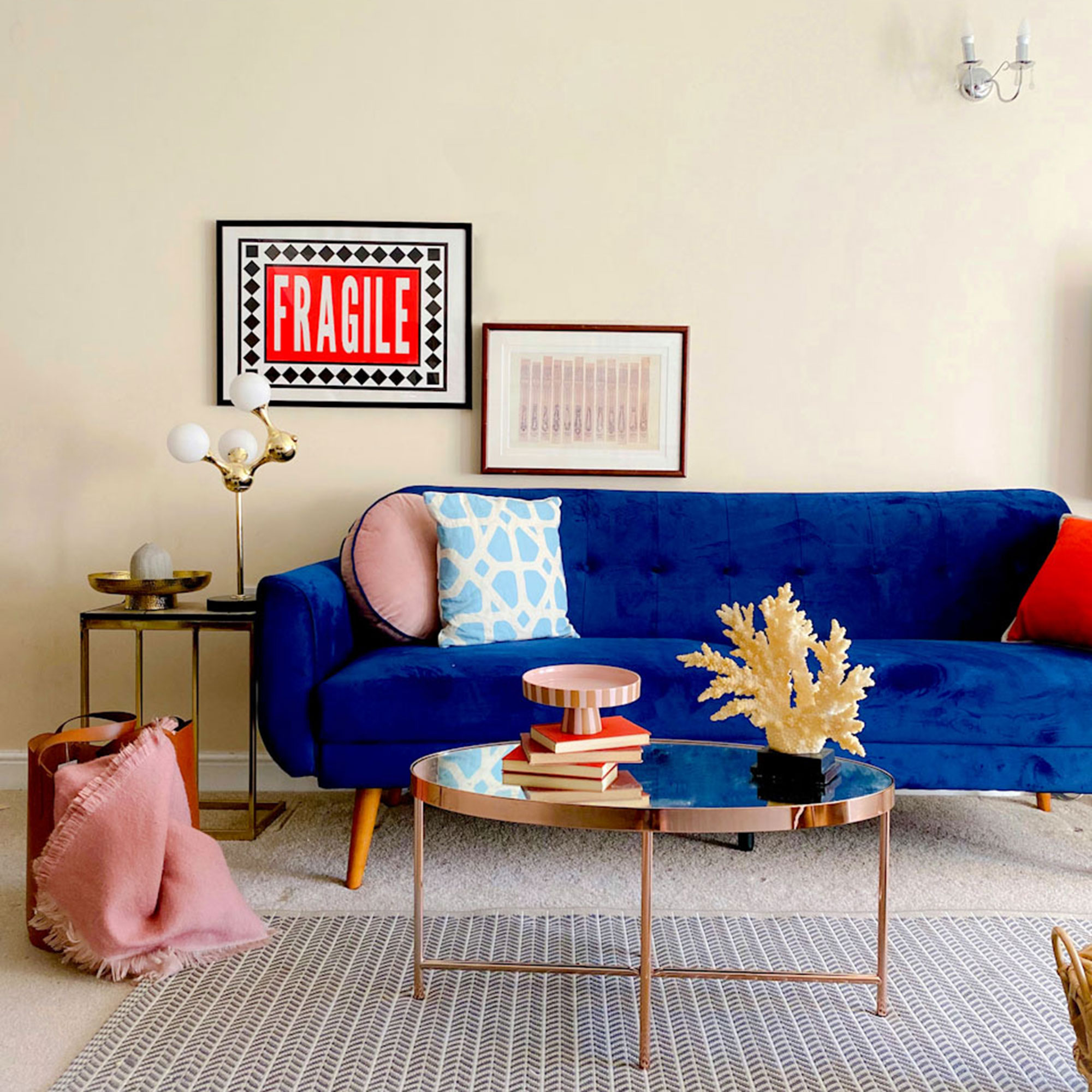 Neutral living room with blue sofa, metallic coffee table and graphic rug