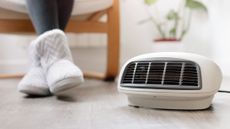 a pic of a woman in winter boots sitting on a chair next to a portable electric heater