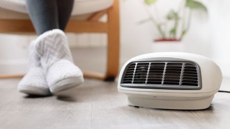 a pic of a woman in winter boots sitting on a chair next to a portable electric heater