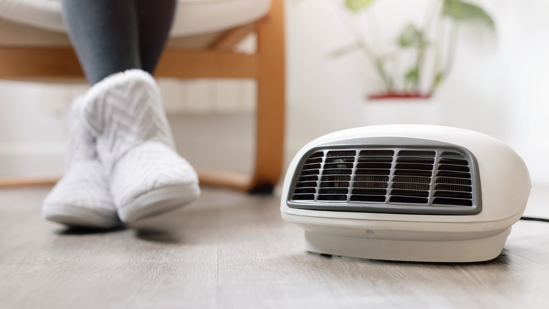 a pic of a woman in winter boots sitting on a chair next to a portable electric heater