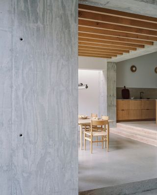 The restrained palette includes exposed timber roof beams and concrete floors