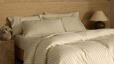 Cozy Earth Soft-Wash Bedding in Coconut/Sandalwood Ticking Stripe pictured in a neutral bedroom area featuring a burl wood side table and oversized natural grain headboard