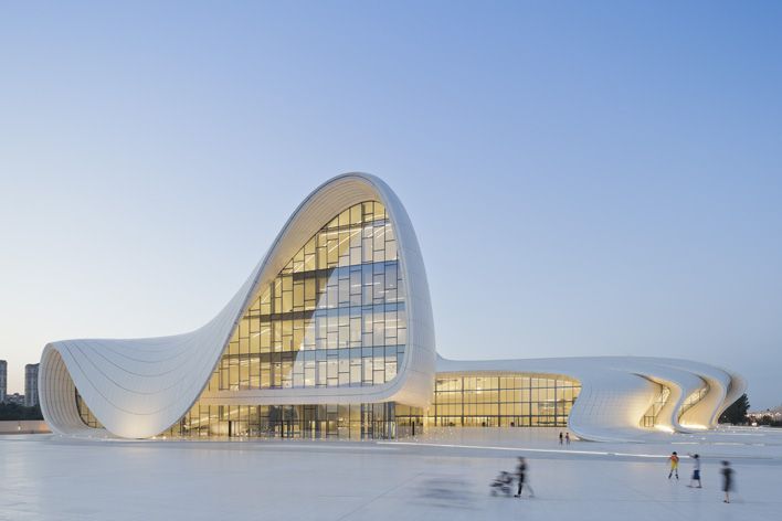 Exterior of the building structure showcasing its sloping roof and clear glass walls. Photographed from a distance with the blue skies in the background