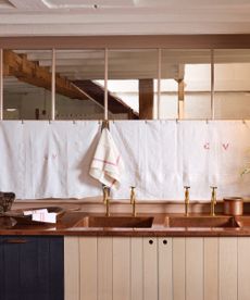 plywood kitchen with copper countertop, brass faucets, double sinks, cafe curtain, wooden bowl,