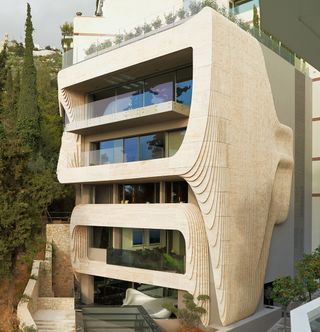 Inspired by the topographic contours of its hilltop location, the building’s facade is made of CNC-cut travertine marble