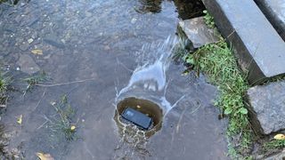 A phone falling into a shallow stream