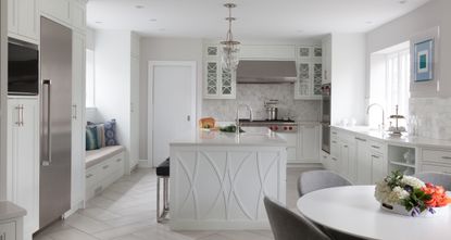 Can kitchen tile be painted: White kitchen with stainless steel appliances, white tiled floor, kitchen island, white countertop, dining table 