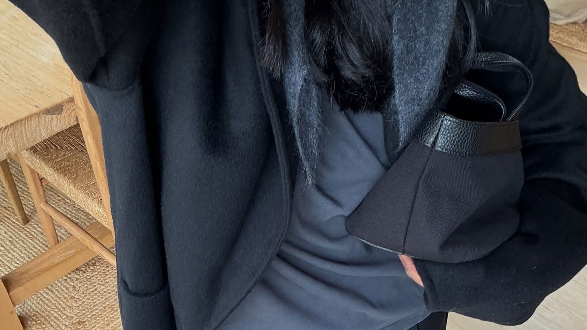 Woman wearing a black jacket over a gray top and scarf.