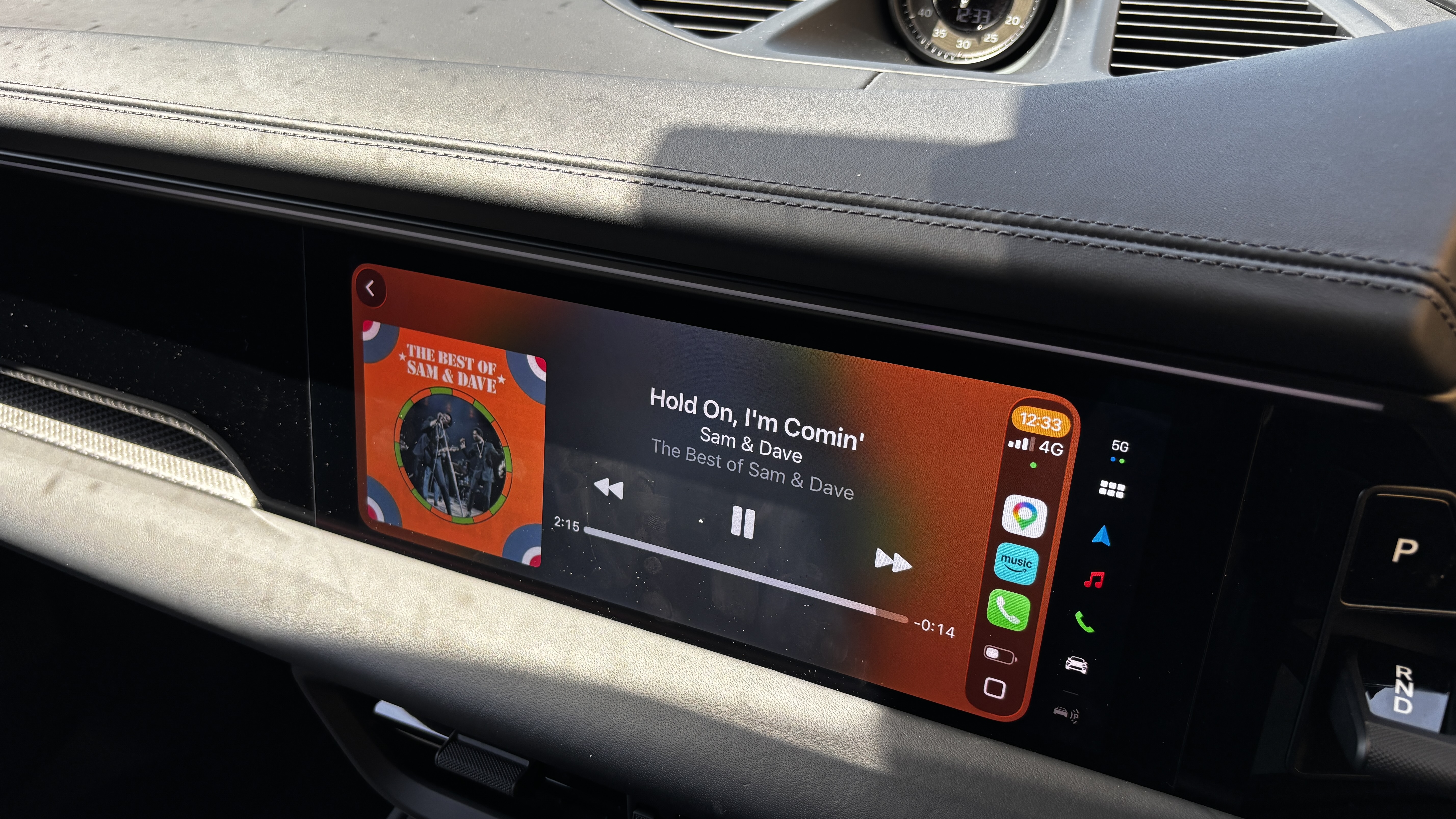 The display of a Porsche Macan Electric showing Apple CarPlay and track information