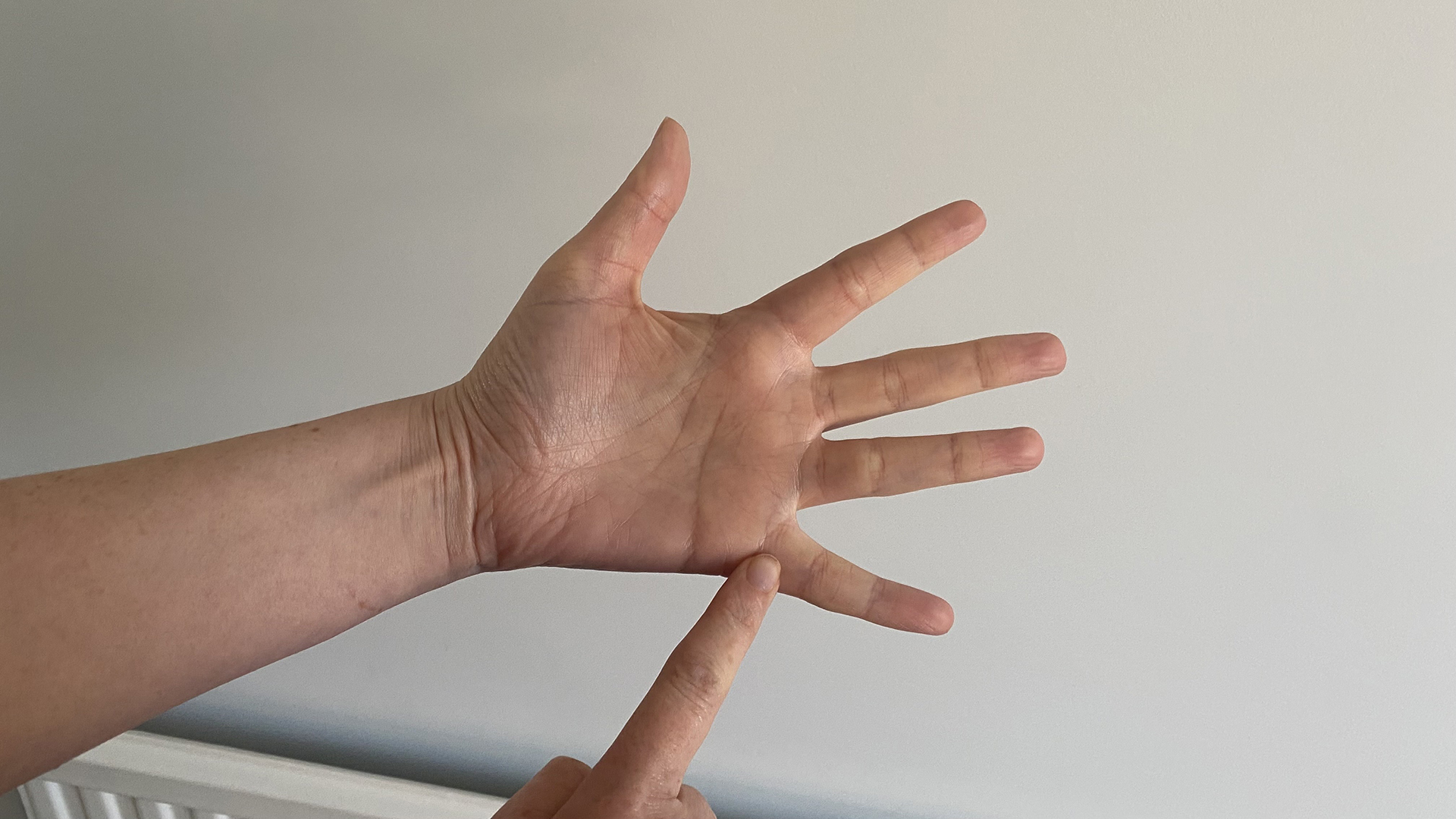 A close up of two hands using the finger breathing relaxation for technique, with the trace finger resting at the base of the pinky finger
