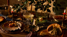 Layered, heirloom-inspired Thanksgiving tablescape featuring ruffled stoneware plates, woven chargers, brass candlesticks, and tapestry-inspired napkins from Magnolia's Thanksgiving 2026 collection