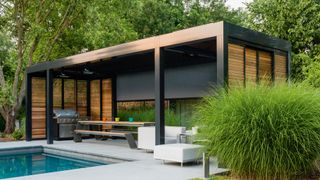 garden black and wood garden room with white outdoor furniture and a huge wooden dining table looking out over onto the pool