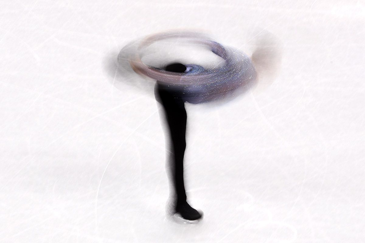 A long-exposure photo shows Adam Rippon whirling on the ice during the figure skating team event.