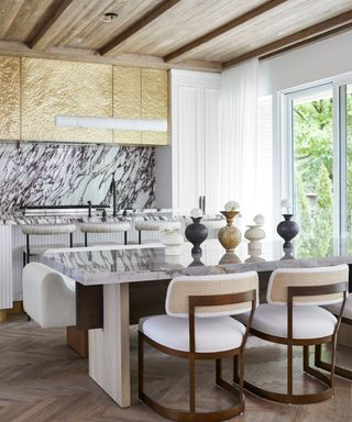 A kitchen and dining room area with busy marble surfaces and lofted wooden ceilings