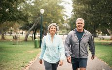 Portrait of an older couple walking through a park and smiling.