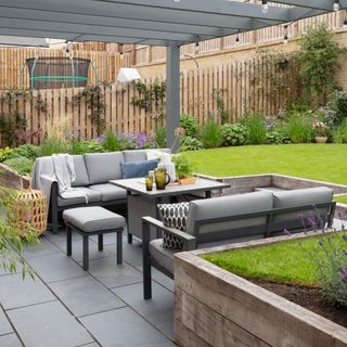 garden furniture sofa with a pergola overhead in a sunken garden with lawn area and paved ground