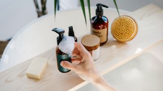 bath products on a wooden bath rack, with a hand reaching out towards them