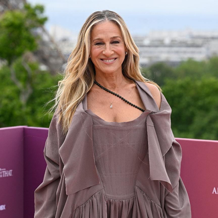 a woman in a long sleeve mauve dress in front of trees with long blonde hair