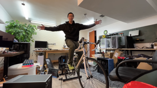 A YouTuber sits on a bike that he is pedalling in order to turn the fan on his CPU.