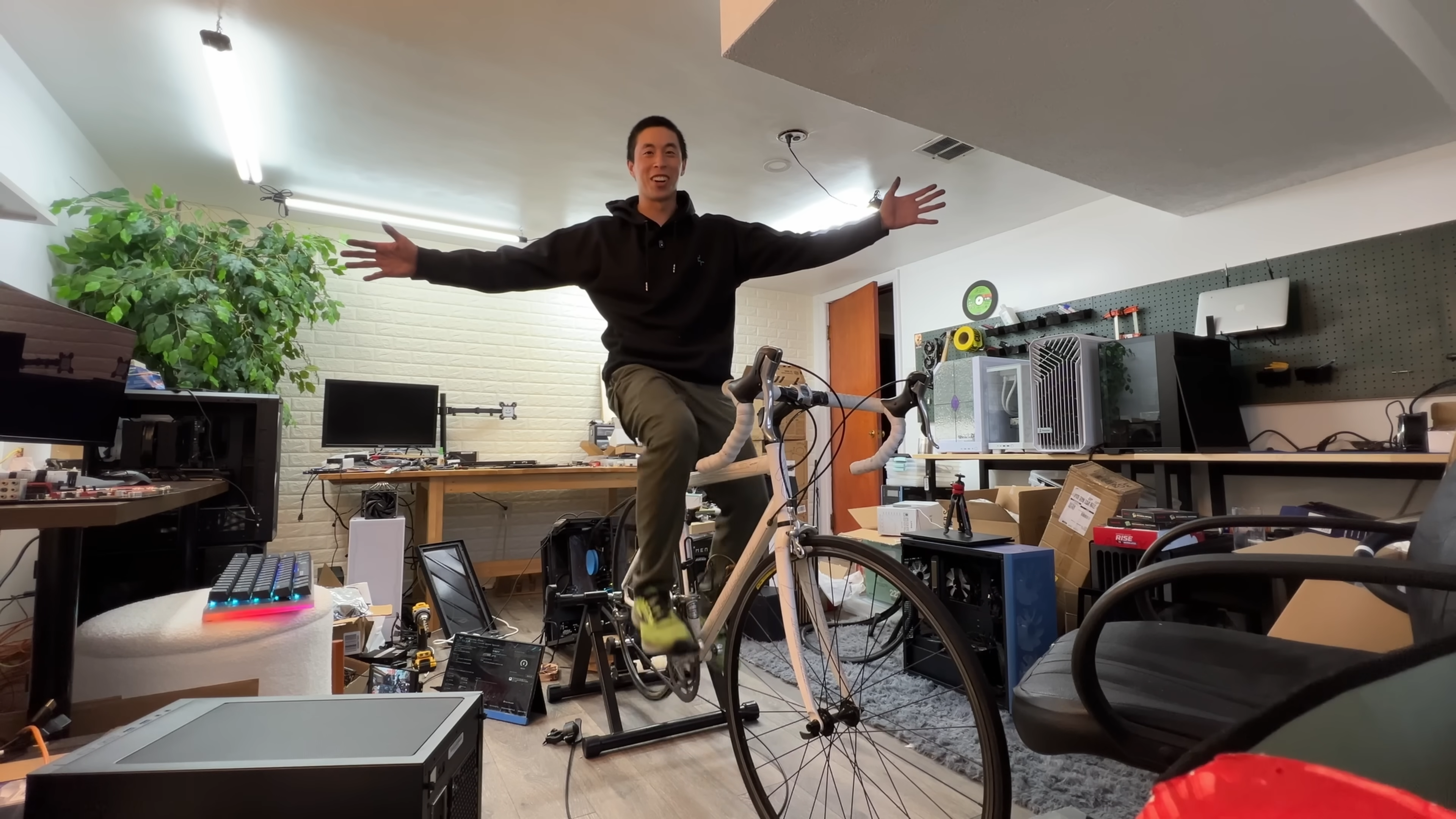 A YouTuber sits on a bike that he is pedalling in order to turn the fan on his CPU.