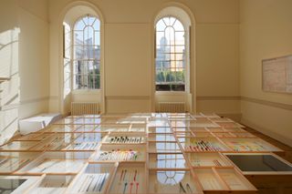 A room with arched windows in Somerset House, with installation of colourful plastic spoons in wooden and glass cases as part of the German Pavilion at London Design Biennale