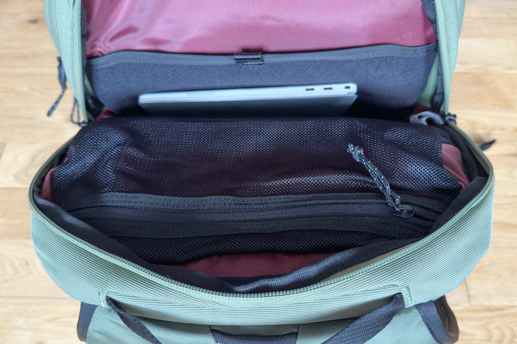Close up of an open Thule rucksack showing the maroon interior and laptop sleeve
