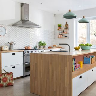 A white kitchen with herringbone metro tiles and wooden worktops