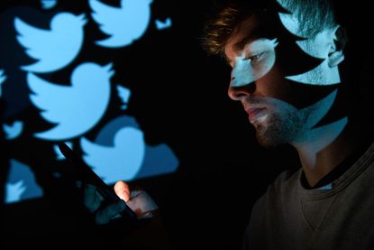The logo for the Twitter social media network is projected onto a man on August 09, 2017 in London, England