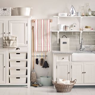 A laundry room with cabinets, drawers and storage boxes
