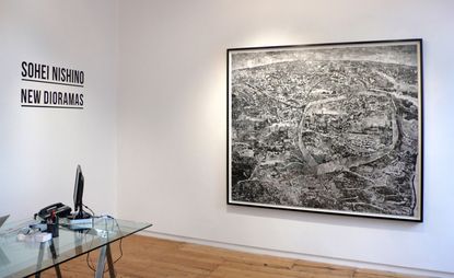 Office with glass desk and large framed black and white landscape image on wall