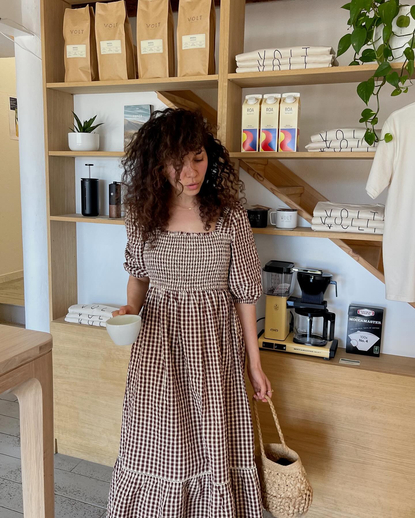 Woman in coffee shop wears gingham dress