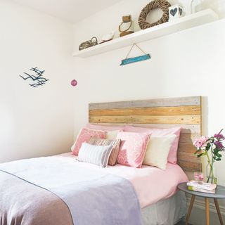 pink and white bedroom with driftwood headboard, pink and grey bedding, shelf with nautical accessories
