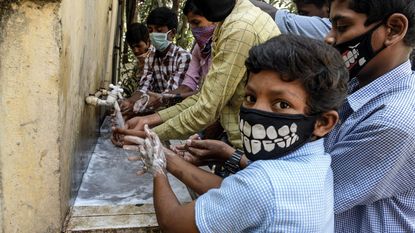 Indian children with facemasks wash their hands © NOAH SEELAM/AFP via Getty Images