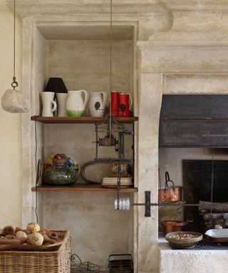 Rustic kitchen shelving built into an alcove in the wall next to an open fire place