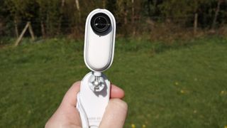 Insta360 GO 2 held up with grass in the background