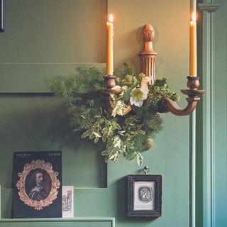 Chrismtas garland on wall sconce on green wall.