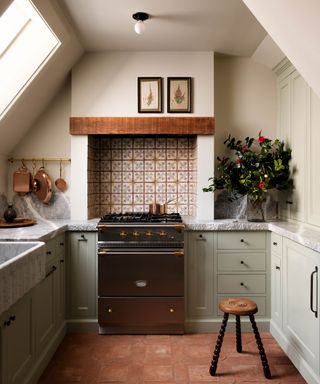 Small sage kreen kitchen with patterned tiles and terracotta floor with marble worktops