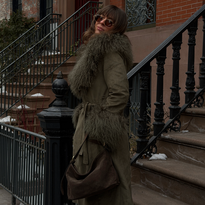 Kathryn Zahorak wearing fur trimmed green coat, sunglasses, brown bag