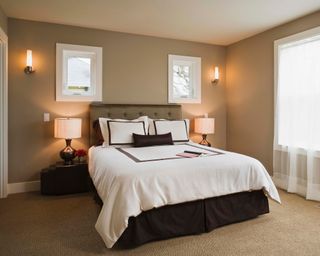 Tidy bedroom with neatly made bed, notebook on top, and bedside lamps on