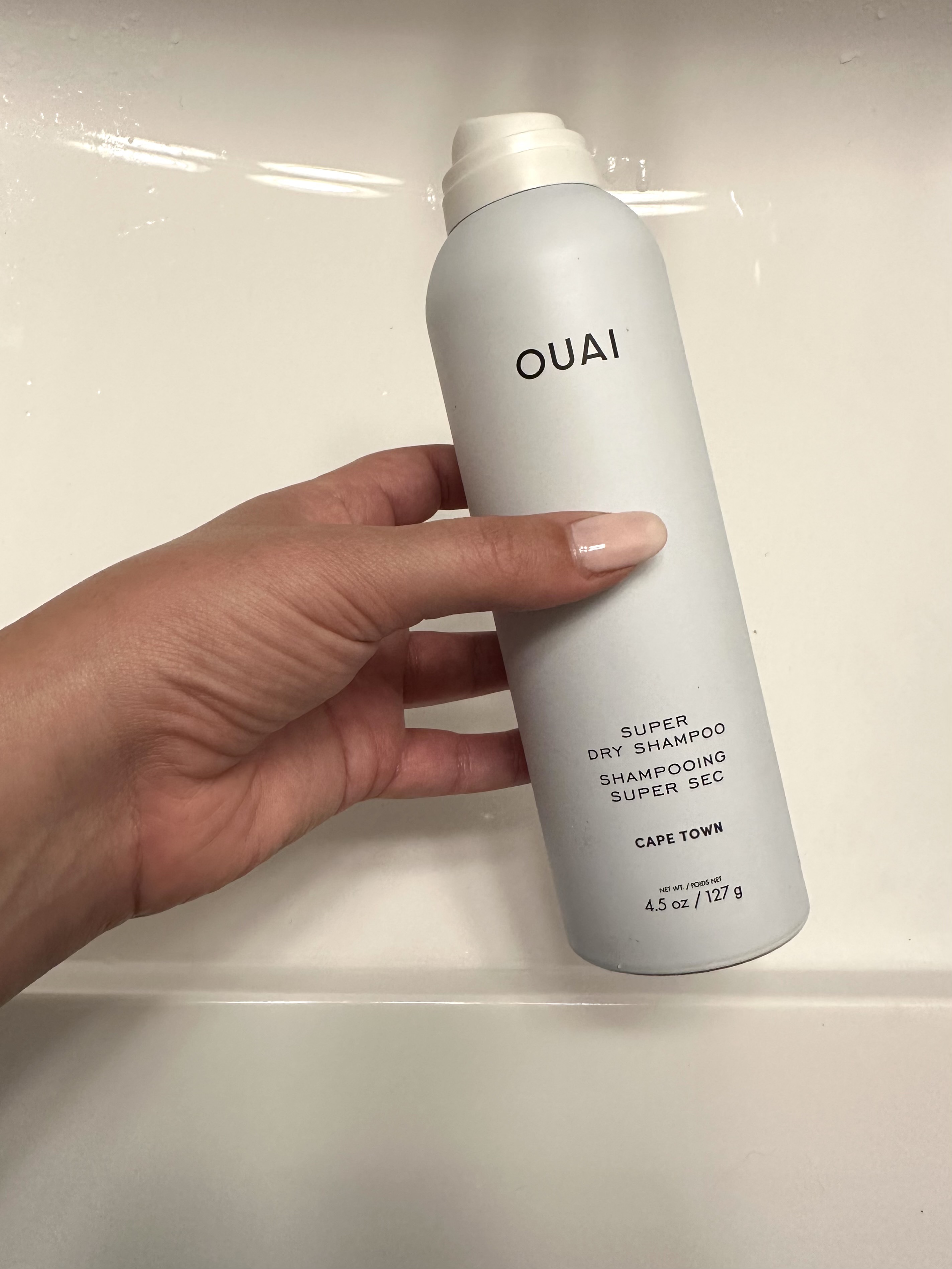 Beauty editor Kaitlyn McLintock holding Ouai Super Dry Shampoo.