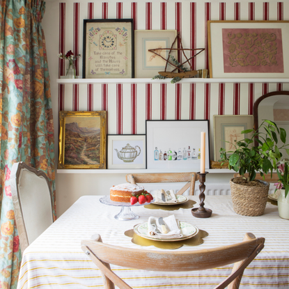 Dining roo with red and white striped walls and a yellow striped tablecloth on the table.