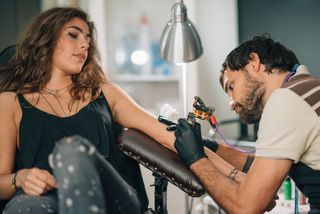 Artist Making Tattoo On Woman Hand At Studio