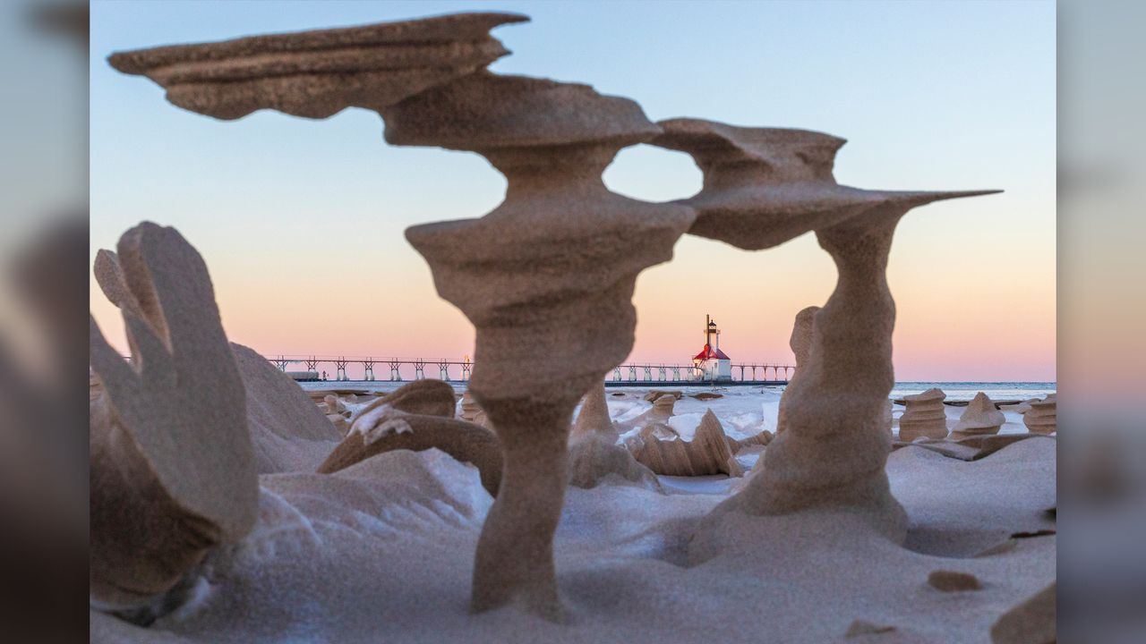 A view of the North Pier Lighthouse through the sand pillars on the beach.