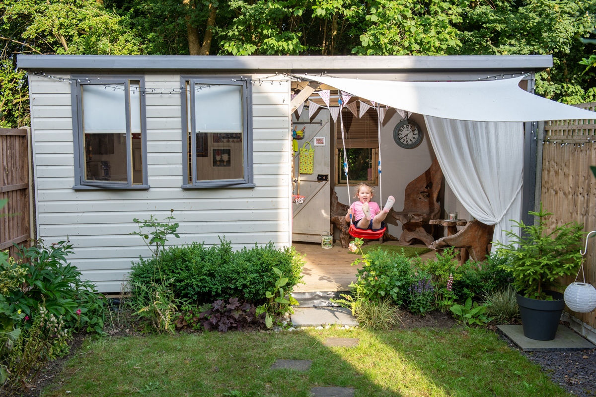 shed painted white with sun sail and white curtain at the door
