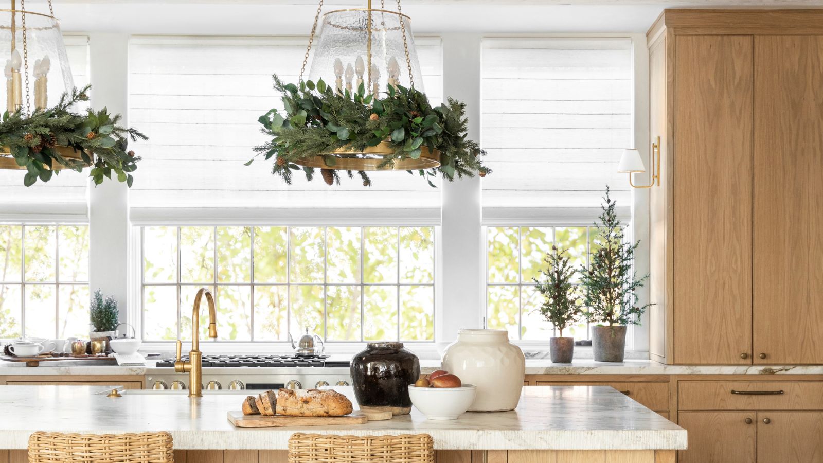 Kitchen with garlands wrapped around lights and mini Christmas trees in the window