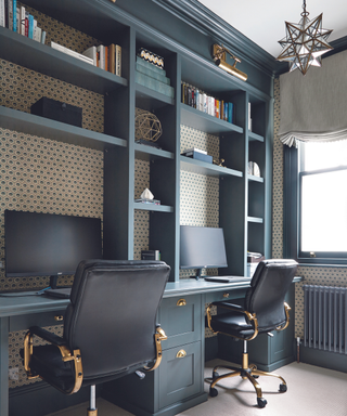 Home office with blue built-in shelves and two black desk chairs